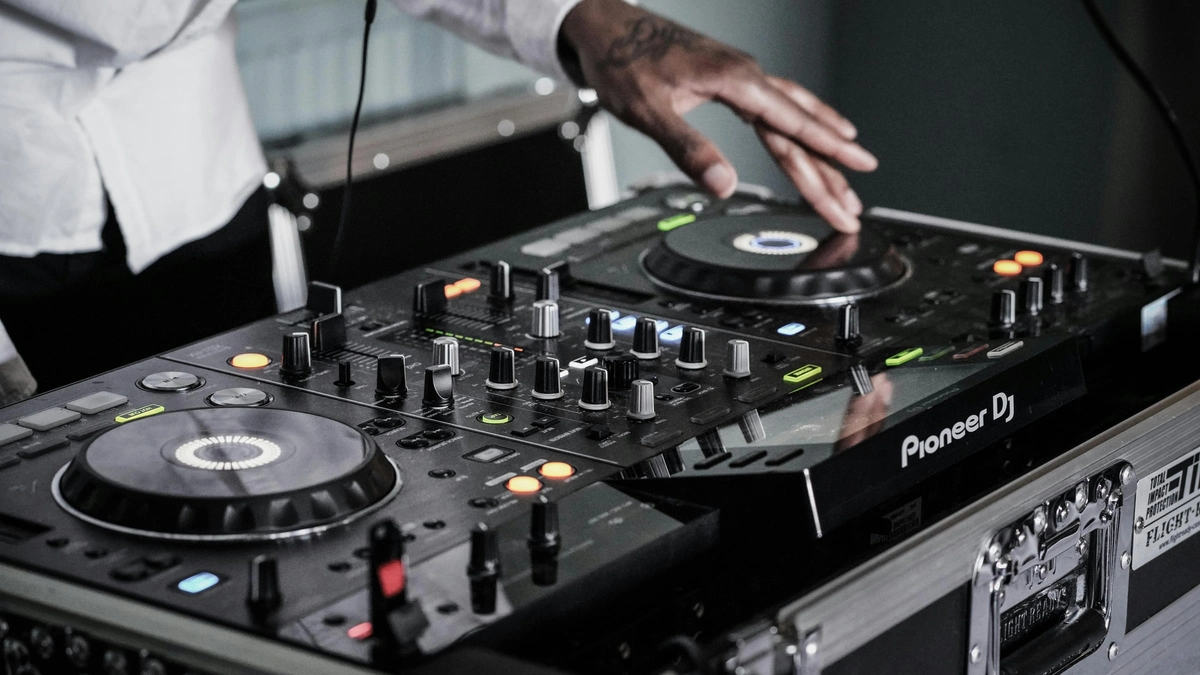 DJ with tattooed hands operating Pioneer DJ controller at wedding reception, housed in flight case